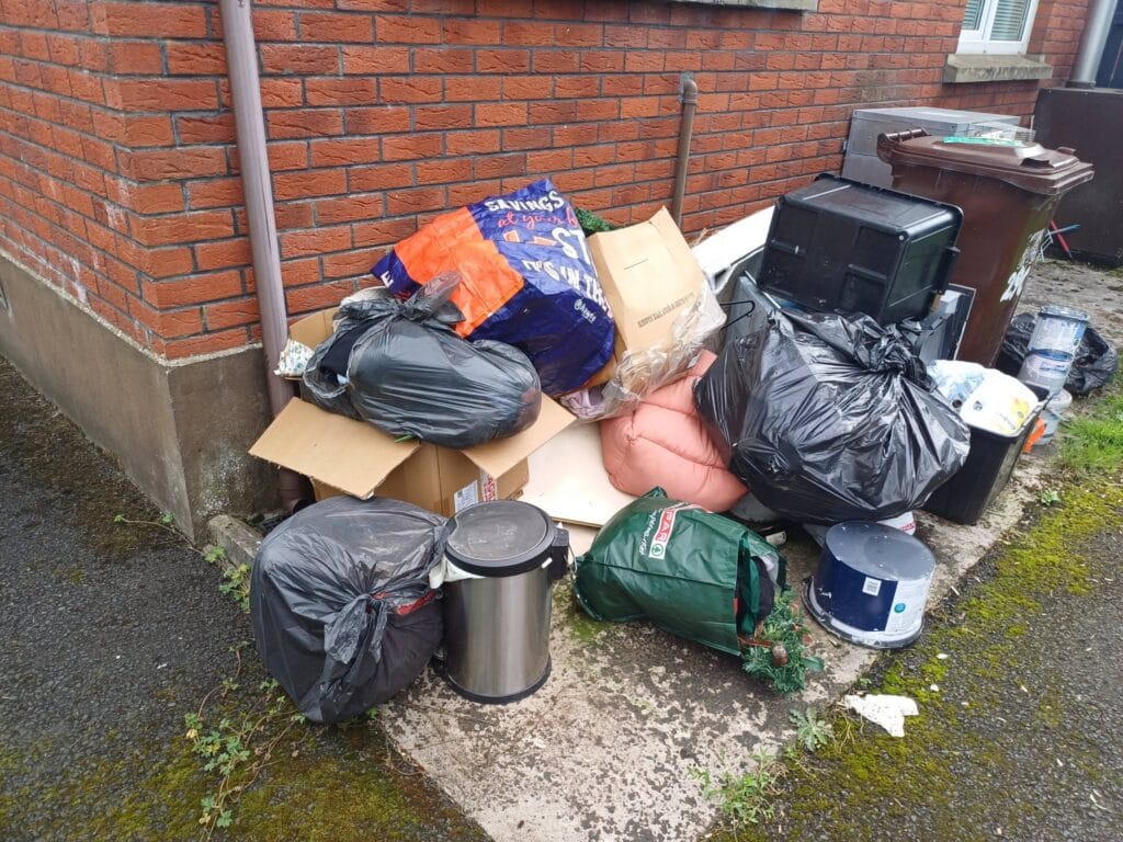 Bags, boxes and household rubbish piled beside a house, waiting for us to collect
